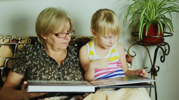 Una chica con su abuela buscando álbum de fotos — Vídeo de stock