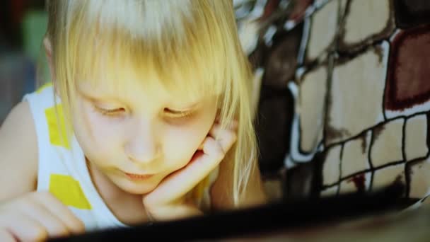 피곤된 어린 소녀는 태블릿을 즐긴다 — 비디오
