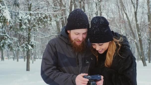 Пара смотрит фотографии на экране камеры — стоковое видео