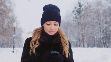 Çekici kadın, kış parkta bir akıllı telefon kullanır