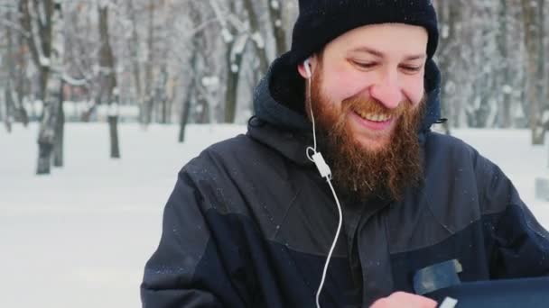 Attraente uomo barbuto utilizza tablet nel parco invernale — Video Stock