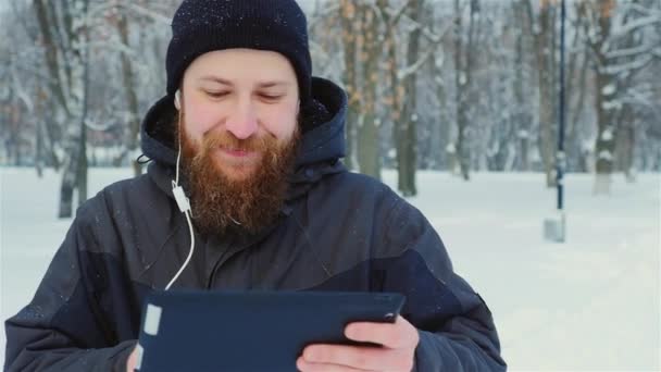 L'uomo barbuto utilizza tablet nel parco invernale — Video Stock