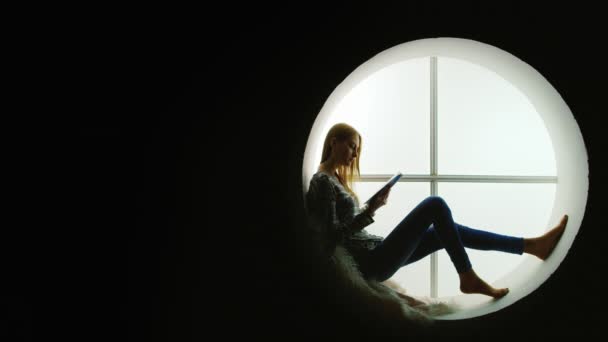 Silhouette di una ragazza che sta leggendo una rivista, un libro — Video Stock