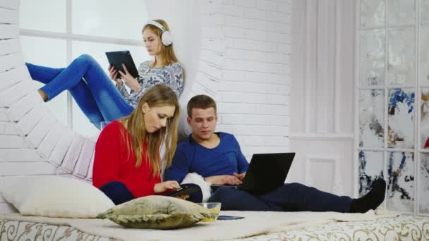 Drei junge Leute entspannen sich mit Gadgets — Stockvideo