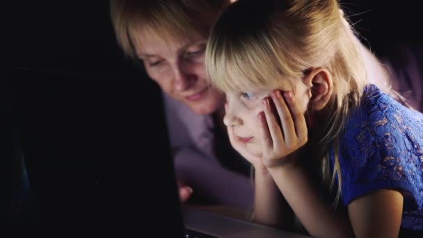 Blauäugiges Mädchen 5-6 Jahre mit Mama, die nachts auf einem Laptop spielt — Stockvideo