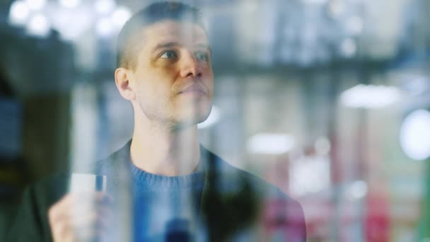 Un hombre guapo está en una vitrina de cristal en una tienda — Vídeo de stock