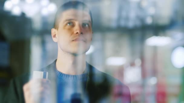 En previsión de las compras, el hombre en la ventana de la tienda — Vídeos de Stock