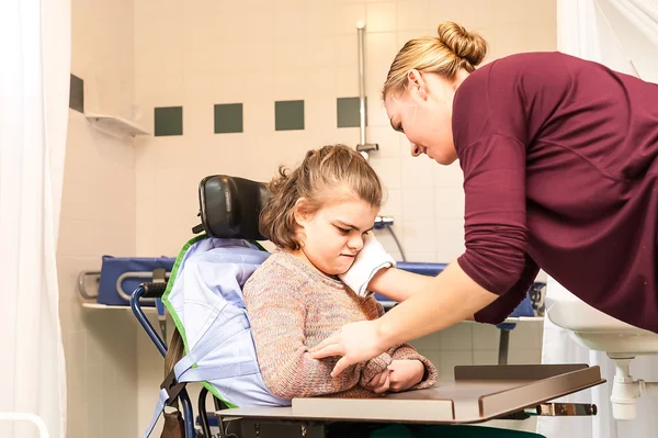 Menina com deficiência em uma cadeira de rodas sendo cuidada por uma enfermeira — Fotografia de Stock