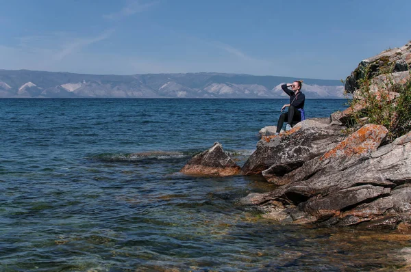 Mulher em uma costa rochosa perto da água do Lago Baikal — Fotografia de Stock
