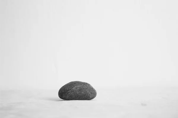 Piedra gris sobre mantel blanco — Foto de Stock