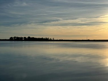 Gün batımında gün doğumunda göl, su, bulutlar, gökyüzü, güneş suya yansıyor..
