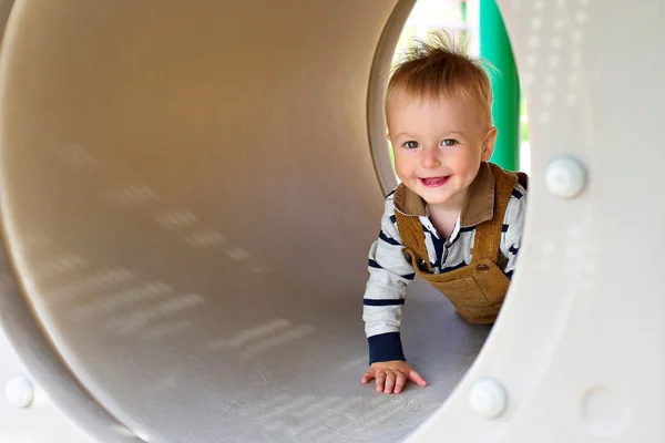 Küçük çocuk gülümseyen peeks Bahçesi tüpü çıkarmak