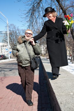 Smiling old-aged man holds the hand of his woman clipart
