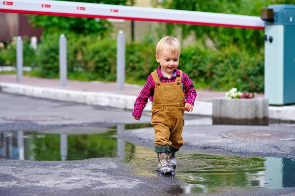Küçük çocuk su birikintileri yürüyor