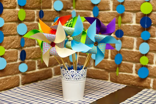 Buket kağıt çok renkli daireler garland ile süslenmiş tuğla duvar önünde yel değirmenleri