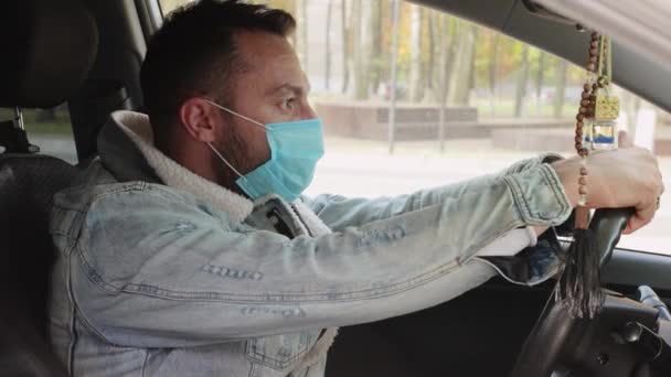 Close-up homem com uma máscara no rosto segurando a roda no carro. — Vídeo de Stock