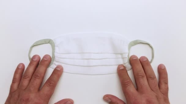 Manliga händer placera långsamt en vit medicinsk mask på bordet. — Stockvideo