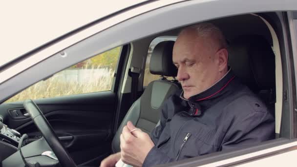 Un hombre conduciendo un coche se pone una máscara médica en la cara.. — Vídeo de stock