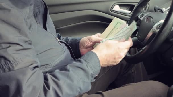 En mand sidder i en bil tæller penge close-up – Stock-video