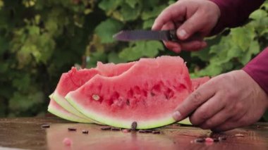 Bir adamın eli bir karpuzu bıçakla parçalara ayırır..