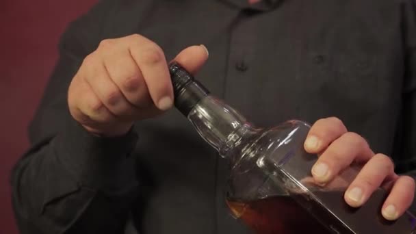 Manliga händer närbild öppnar en flaska whisky. — Stockvideo