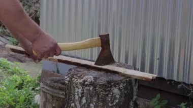 Erkek eli baltayla bir kütüğü keser..
