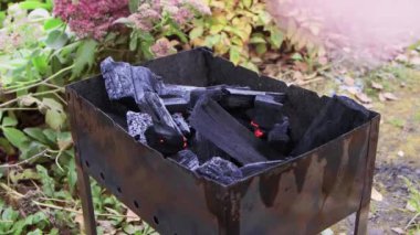 Bir adamın eli alev alev yanan kömürlerin üzerine vantilatörle hava üflüyor..