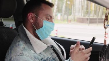 Arabada yüzünde maske olan bir adam bize bakıyor..