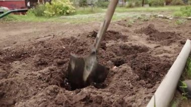 Yakın plan bir kürek gübreyi küçük bir delikte karıştırır..