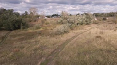 Yeşil ağaçlı bir tarlada, köy yolunda alçak uçuş..