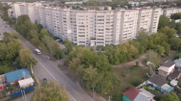 Vuelo bajo sobre una calle de la ciudad con un edificio de varios pisos. — Vídeo de stock