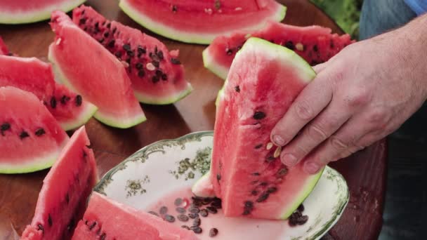 Primeros planos manos masculinas cortar la sandía sobrante en rodajas con un cuchillo. — Vídeos de Stock