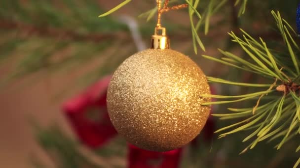 Op kerstavond hangt een gouden bal aan de boom en zwaait.. — Stockvideo