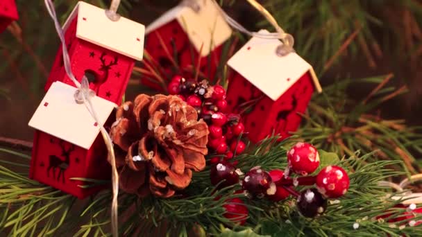 En la noche de Navidad, un cono de pino y una guirnalda roja se balancean en el árbol. — Vídeo de stock