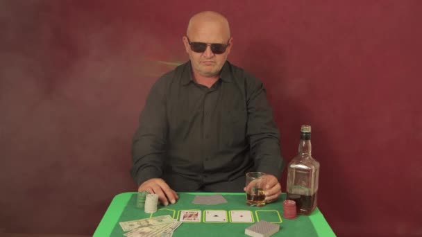 Ein Mann im Casino an einem Spieltisch dreht mit der Hand ein Glas. — Stockvideo