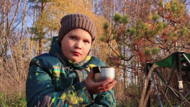 Chlapec na pozadí žluté listí pije čaj a ukazuje třídu. — Stock video