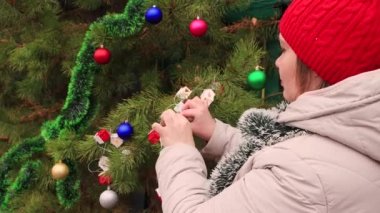 Kırmızı şapkalı genç kadın altın renkli bir balon asıyor..