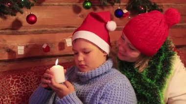 Kırmızı şapkalı anne ve oğlu beyaz bir Noel mumunu inceliyor..