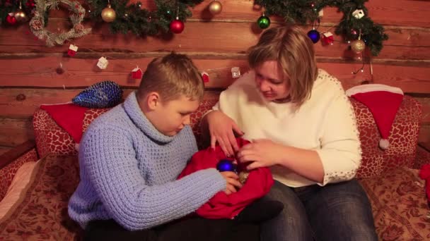 男の子と彼の母親は赤い袋からクリスマスボールを取り出します. — ストック動画