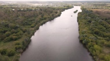 Yeşil kıyıları olan geniş bir nehrin üzerinden uçmak. 