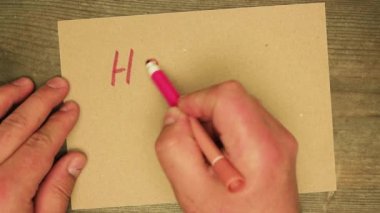Erkek el, kırmızı keçeli kalemle karton çarşafa mutlu bir tatil yazar..