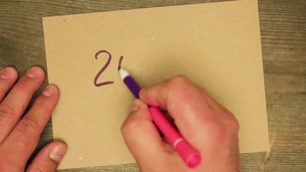 Une main masculine écrit avec un stylo feutre violet sur une feuille de carton 2020 stop. — Video