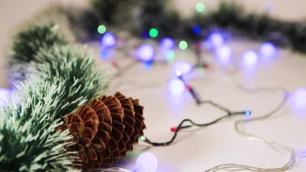 Groene tinsel en dennenappel, kerstboom decoratie met bokeh aan de achterkant. — Stockvideo