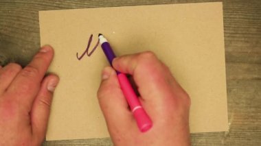 Erkek el, keçeli kalemle karton çarşafa yazar Mutlu Noeller. 