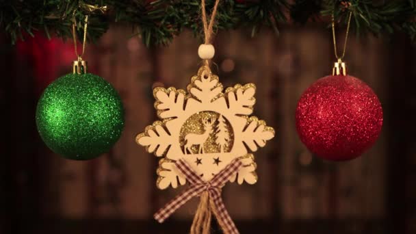 Decorazione di Natale, palle rosse e verdi e un fiocco di neve di legno su un ramo. — Video Stock