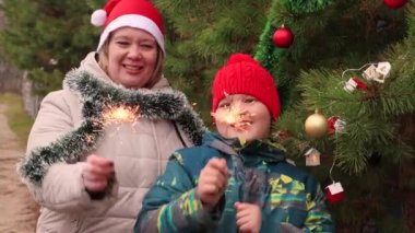 Oğlan ve annesi neşeyle maytap sallar ve dans ederler..