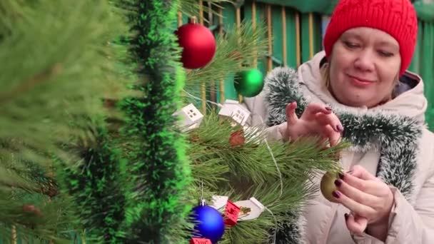 Gros plan jeune femme au bonnet rouge accroche un ballon festif et sourit. — Video