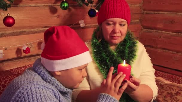 Η μαμά κρατάει ένα κόκκινο χριστουγεννιάτικο κερί, ο γιος το εξετάζει.. — Αρχείο Βίντεο