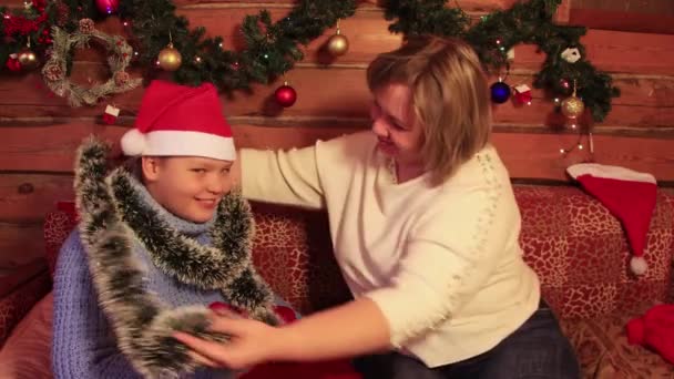 Mamá viste a un hijo alegre en una boa de Navidad. — Vídeos de Stock