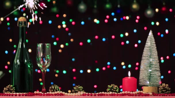 Na stole jest szampan, szklanka, drzewo i szyszki, pali się świeca — Wideo stockowe